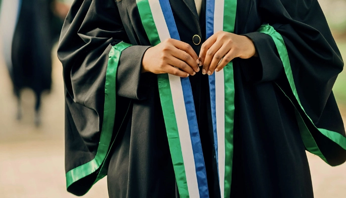 Half-length portrait of a woman in a graduation gown, symbolizing the transformative power of education and the long-term impact Baino Social Impact strives to create for girls who overcome hardship to achieve success.
