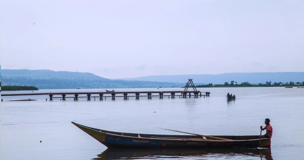 A local boat glides across wide Ugandan waters, with two other boats visible in the distance. The image symbolizes the journey, perseverance, and the long path undertaken to sustain Baino Social Impact, connecting efforts in Uganda with support from abroad.